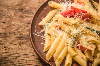 Klasik İtalyan makarnası, kabaklı ve domatesli. Kırsal bir masada kil tarakta. Üst manzara, bir tarif için kopyalama alanı.