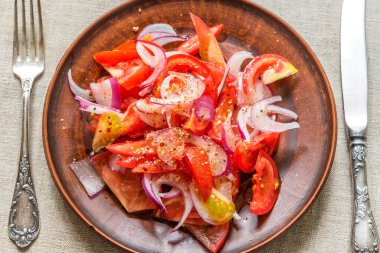 Kırsal bir çömlek üzerinde domates ve kırmızı soğan salatası.