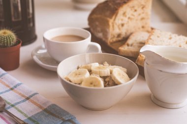 Kahvaltıda muzlu yulaf ezmesi ve sütlü kahve. Yakın plan, açık kırsal arka plan.