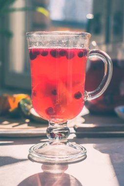 Sabah güneşiyle aydınlanan, kırsal bir masada kızılcık içeceği olan bir bardak. Sağlıklı yaşam kavramı.