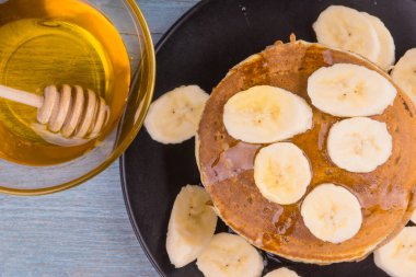 Lezzetli geleneksel Amerikan krepleri, dilimlenmiş muz ve bal, üst manzara.