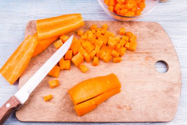 Vejetaryen çorbası için tahta bir tahtaya havuç dilimlenmiş.