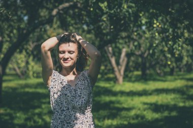 Genç ve çekici bir kadın bahçede saçını düzeltiyor.