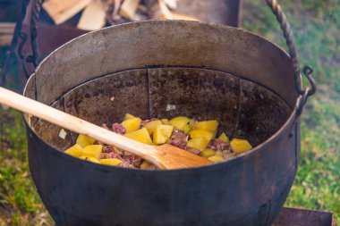 Dışarıdaki eski demir bir tencerede et ile haşlanmış patates.