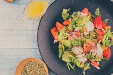 Tahta arka planda siyah tabakta taze vegan salatası, kopyalama alanı - sağlıklı beslenme kavramı