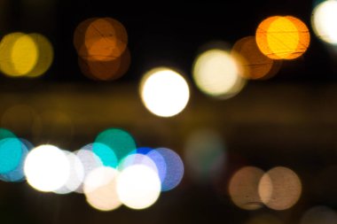 Gece şehir sokaklarının arka planında parlak araba farları var.