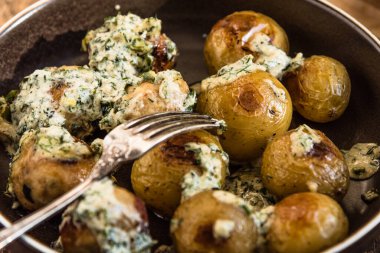 İsveç yemekleri. Krema soslu geleneksel tavuk köfteleri ve ahşap arka planda yeni patatesler.