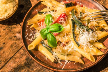 Klasik İtalyan makarnası, kabaklı ve domatesli. Kır tabağında, kır manzaralı.