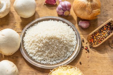 Kırsal ahşap bir masada mantarlı risotto için malzemeler.