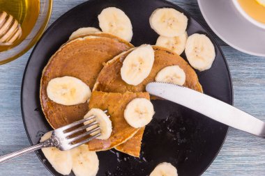 Lezzetli geleneksel Amerikan krepleri, dilimlenmiş muz ve bal, üst manzara.