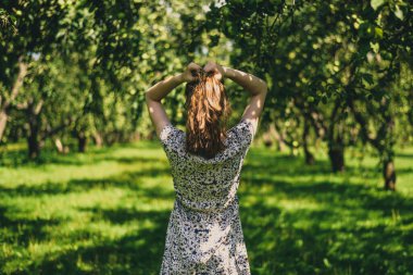 Genç ve çekici bir kadın bahçede saçını düzeltiyor.
