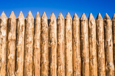 Wooden fence made of sharpened planed logs clipart