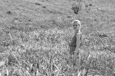 Güzel genç bir kadın bulutlu mavi gökyüzüne karşı çayırda yürüyor.