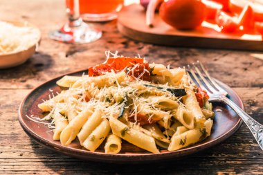 Klasik İtalyan makarnası, kabaklı ve domatesli. Eski ahşap masa üzerinde kil bir kaplumbağa.