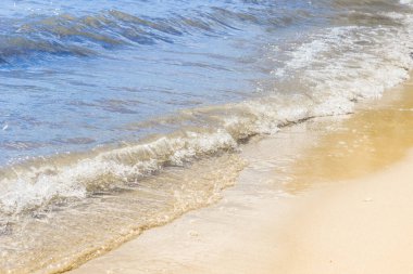 Güneşli bir günde, deniz kıyısında mavi dalgalar ve sarı kumlar, rahatlama kavramı.