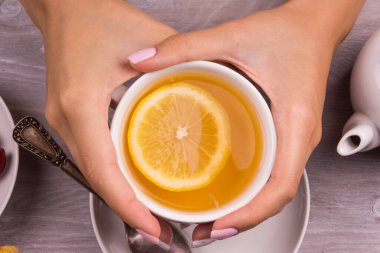 Bir fincan çay ve manikürlü genç bir kızın elleri.