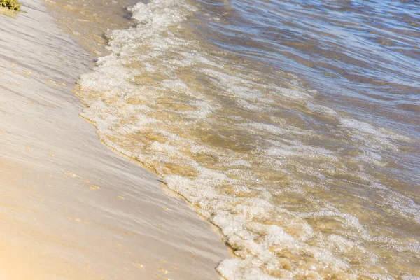 Blue waves on a yellow sandy beach - close-up