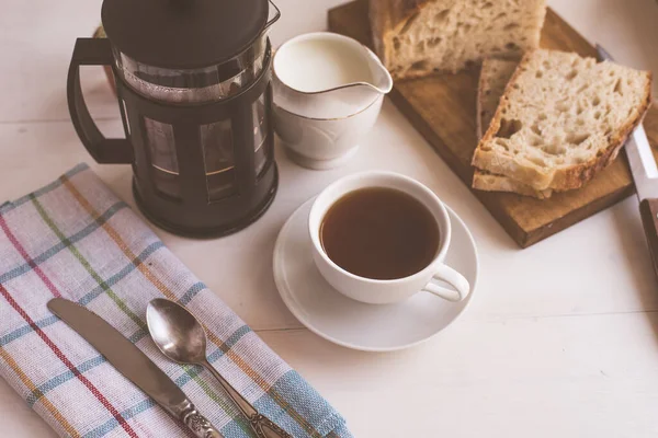 Breakfast - a cup of coffee, french press and fresh bread