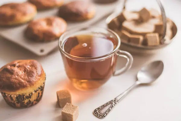 Ein Glas Tee Und Frisch Gebackene Muffins Auf Dem Tisch — Stockfoto