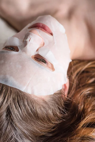 Seorang Wanita Muda Berbaring Dengan Lembar Topeng Kosmetik Latar Belakang — Stok Foto