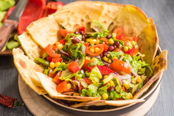 Traditional Mexican vegetarian taco salad with avocado, corn, pepper, tomatoes and beans
