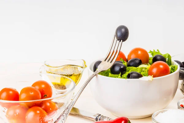 Vegetarian salad and ingredients, peppers, olives, spices and olives on the fork - a concept of healthy nutrition