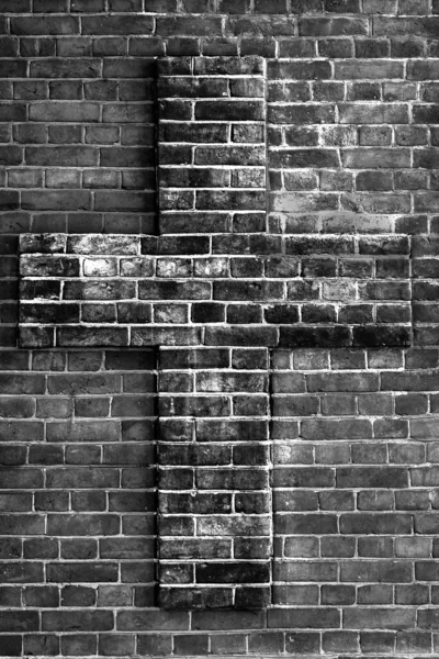 Relief cross on a brick wall - black and white background, texture