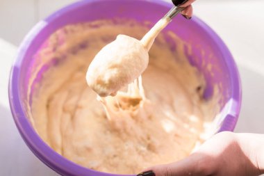 Kek hamuruyla dolu bir kase pencere kenarında büyük bir kase ve bir kaşık