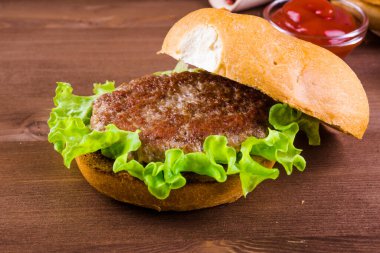 Lezzetli bir ev yapımı hamburger, malzemeler - kızarmış çörek, pirzola, marul, domates, soğan ve sos.