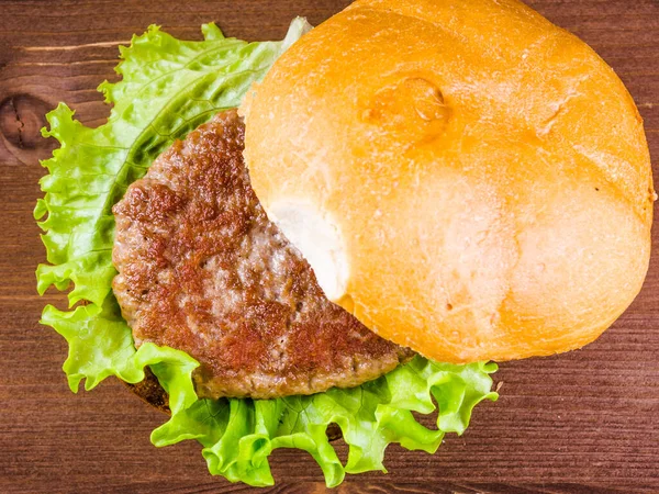 Cooking a delicious homemade burger, ingredients - fried bun, cutlet, lettuce, tomato, onion and sauce