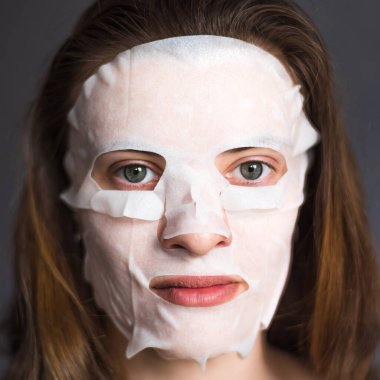 Nemlendirici mendil maskeli güzel kahverengi saçlı bir kadının portresi.