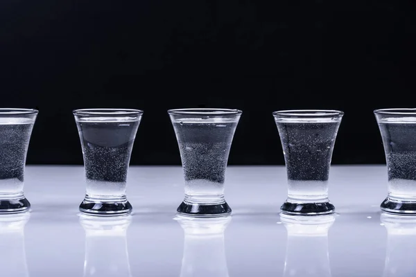 Siyah Arka Planda Beyaz Bir Masada Votkalı Bardaklar — Stok fotoğraf