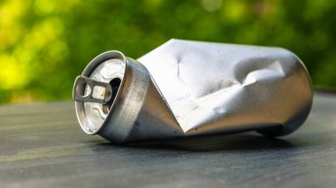 İçkinin altındaki buruşmuş alüminyum gümüş teneke kutu. Çevre kirliliği kavramı.