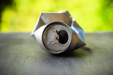 İçkinin altındaki buruşmuş alüminyum gümüş teneke kutu. Çevre kirliliği kavramı.