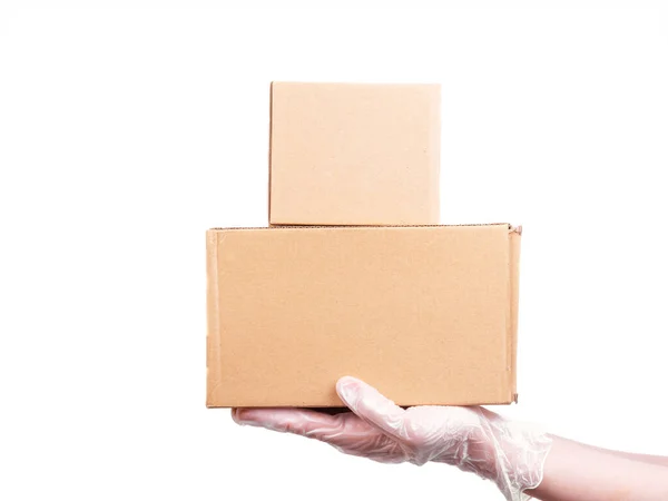 Female hand in a disposable transparent glove holds 2 cardboard boxes - safe delivery of goods, isolate on a white background, copy space