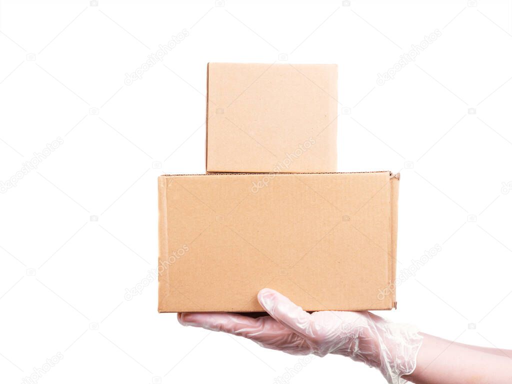 Female hand in a disposable transparent glove holds 2 cardboard boxes - safe delivery of goods, isolate on a white background, copy space