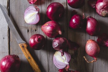 Eski bir ahşap masanın üzerinde yatan kırmızı soğan ampuller.