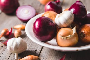 Eski bir ahşap masa üzerinde duran beyaz bir plaka farklı soğan ampuller birkaç tür.