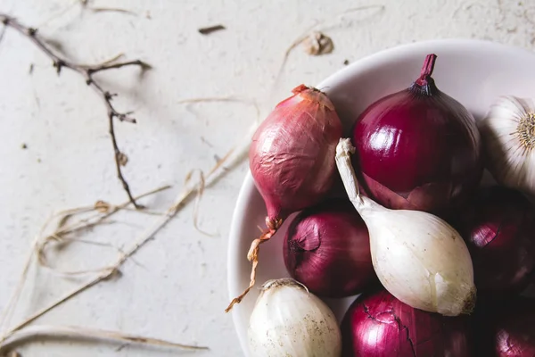 Ampoules à oignons rouges et blancs dans l'assiette sur une vieille table peinte en bois — Photo