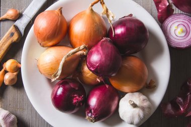 Eski bir ahşap masa üzerinde duran beyaz bir plaka farklı soğan ampuller birkaç tür.