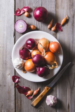 Eski bir ahşap masa üzerinde duran beyaz bir plaka farklı soğan ampuller birkaç tür.