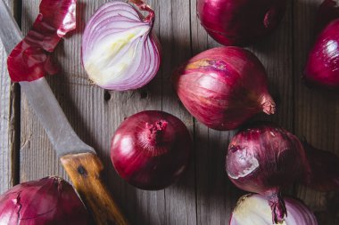 Eski bir ahşap masanın üzerinde yatan kırmızı soğan ampuller.