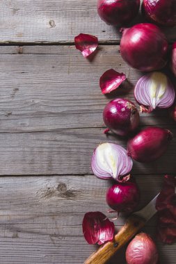 Eski bir ahşap masanın üzerinde yatan kırmızı soğan ampuller.