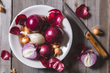 Eski bir ahşap masa üzerinde duran beyaz bir plaka farklı soğan ampuller birkaç tür.
