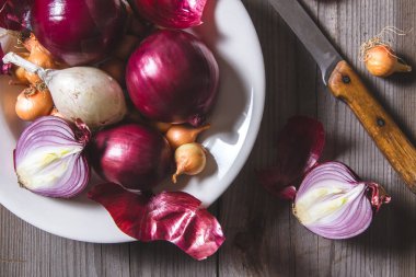 Eski bir ahşap masa üzerinde duran beyaz bir plaka farklı soğan ampuller birkaç tür.