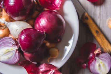 Eski bir ahşap masa üzerinde duran beyaz bir plaka farklı soğan ampuller birkaç tür.