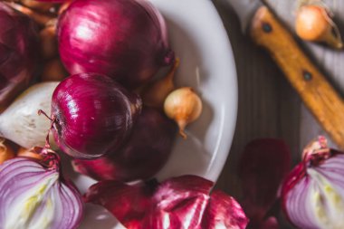 Eski bir ahşap masa üzerinde duran beyaz bir plaka farklı soğan ampuller birkaç tür.