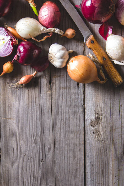 Несколько видов луковых луковиц лежащих на старом деревянном столе
.
