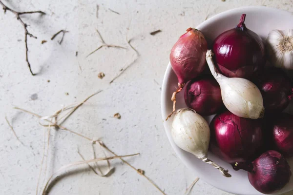 Ampoules à oignons rouges et blancs dans l'assiette sur une vieille table peinte en bois — Photo