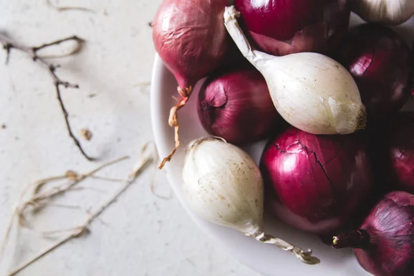 Ampoules à oignons rouges et blancs dans l'assiette sur une vieille table peinte en bois — Photo